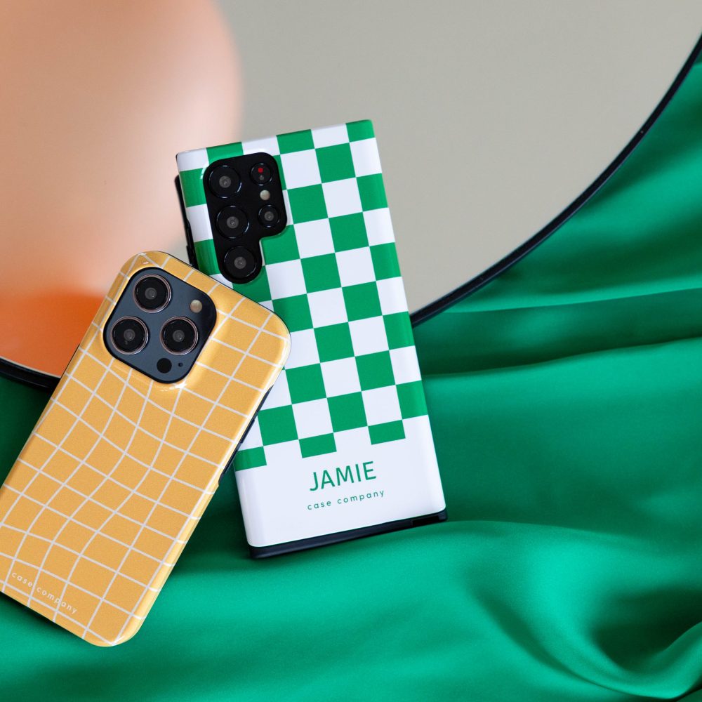 Zwei robuste Hüllen: eine gelb karierte für ein iPhone und eine mit grünem Schachbrettmuster und dem Namen Jamie